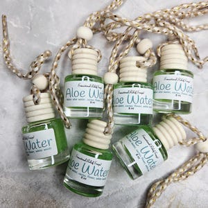 May include: A white ceramic mug with a black handle and the text "But First, Coffee" in a bold, black font. The mug is set against a blurred background, highlighting its clean design.