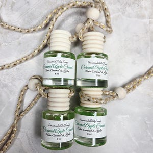May include: Four small glass bottles of "Caramel Apple Crunch" fragrance, each with a white label and a light green liquid. The bottles are connected by a decorative rope with wooden beads. The text "Sensational Relief Soap" is also visible.