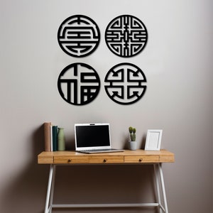 May include: Four black circular wall decor pieces with intricate geometric designs. The decor is mounted on a white wall above a wooden desk with a laptop, books, and a potted plant.