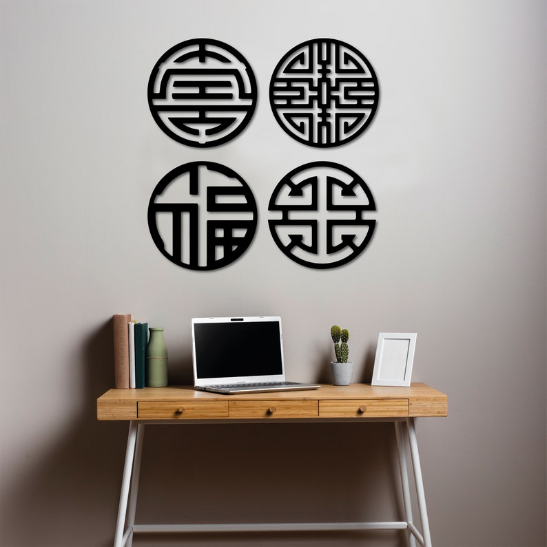 May include: Four black circular wall decor pieces with intricate geometric designs. The decor is mounted on a white wall above a wooden desk with a laptop, books, and a potted plant.