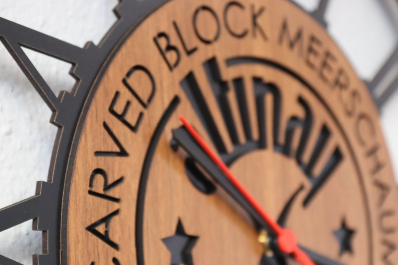 May include: A wooden clock with black hands and a red second hand. The clock face has a black carved design and the words "Carved Block Meerschaum" around the edge.