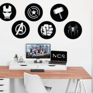 Puede incluir: Un escritorio blanco con una superficie de madera y cajones blancos. Un port&aacute;til y un ordenador de sobremesa est&aacute;n sobre el escritorio. Hay seis pegatinas de pared redondas en blanco y negro con logotipos de superh&eacute;roes en una pared blanca detr&aacute;s del escritorio. Los logotipos incluyen Iron Man, Capit&aacute;n Am&eacute;rica, Thor, Hulk, Avengers y Spiderman.