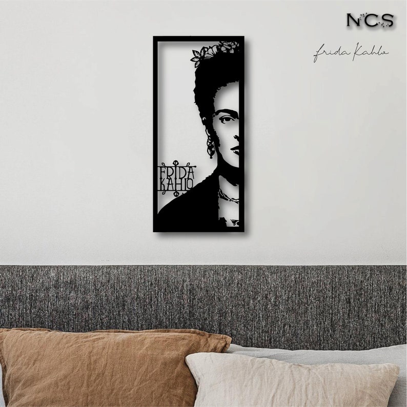 May include: Black and white metal wall art featuring a portrait of Frida Kahlo with the text "Frida Kahlo" in a stylized font.