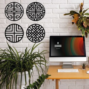 May include: Four black metal wall decor pieces with geometric designs. The designs are circular and feature intricate patterns. The decor is mounted on a white brick wall.