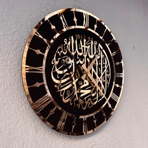 May include: A black and gold clock with Roman numerals and Arabic calligraphy. The clock face features the Islamic phrase "Allah" in gold lettering.