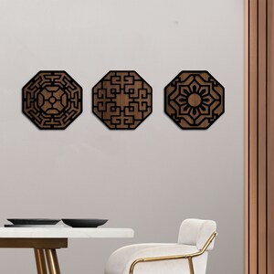 May include: Three wooden wall decorations in the shape of octagons with intricate geometric designs. The designs are in black and the wood is a dark brown colour.