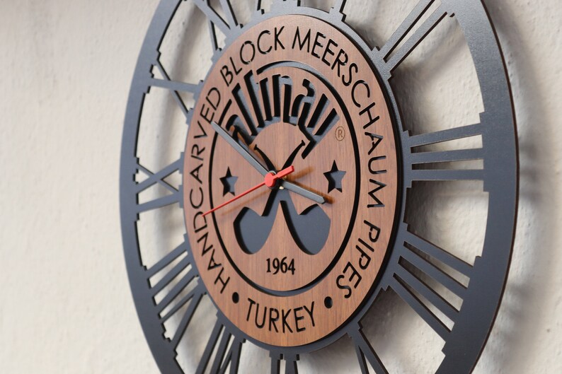 May include: A black and brown wall clock with Roman numerals and a wooden center featuring the text "Handcarved Block Meerschaum Pipes 1964 Turkey".