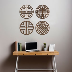 May include: Four brown wooden wall decor pieces with geometric designs, a laptop computer, a small potted plant, and a white picture frame on a wooden desk with white legs.