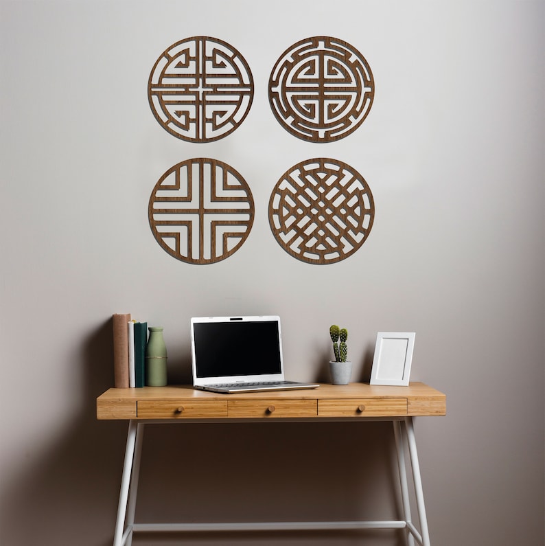 May include: Four brown wooden wall decor pieces with geometric designs, a laptop computer, a small potted plant, and a white picture frame on a wooden desk with white legs.