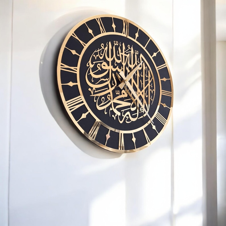 May include: A black and gold clock with Roman numerals and Arabic calligraphy. The clock is on a white wall.