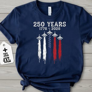 A navy blue t-shirt with a graphic design featuring a flag and four airplanes, along with the text "250 YEARS 1776 - 2026" printed on it.