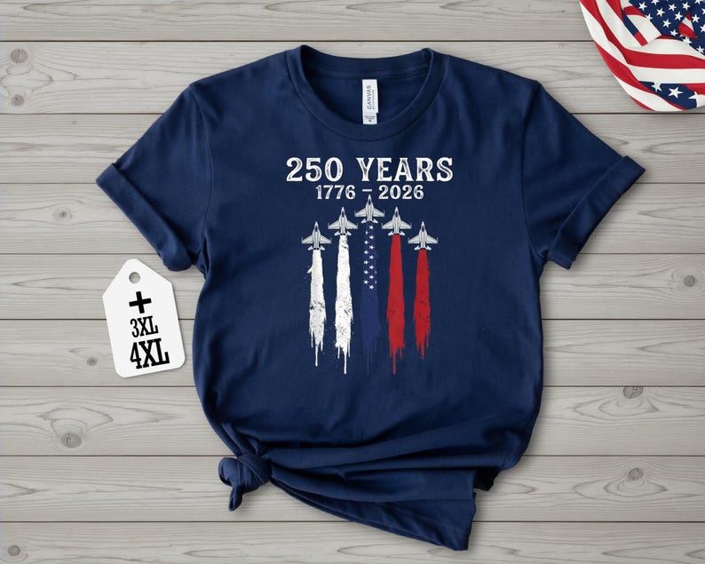 A navy blue t-shirt with a graphic design featuring a flag and four airplanes, along with the text "250 YEARS 1776 - 2026" printed on it.