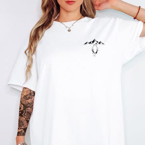 A woman wearing a white t-shirt with a graphic design on the front.