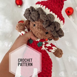 May include: A handmade crochet doll wearing a red Santa hat with white trim and a matching red outfit. The doll has brown hair and a fair complexion. The text "CROCHET PATTERN" is overlaid on the image.