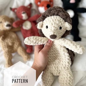 Puede incluir: Un patrón de crochet para un juguete de peluche de erizo. El erizo es beige con la cabeza marrón y los ojos negros. El patrón está disponible para descargar.