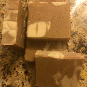 Puede incluir: Cuatro barras de jabón hecho a mano con un patrón de remolino marrón y blanco. El jabón está hecho con ingredientes naturales y es perfecto para pieles sensibles.