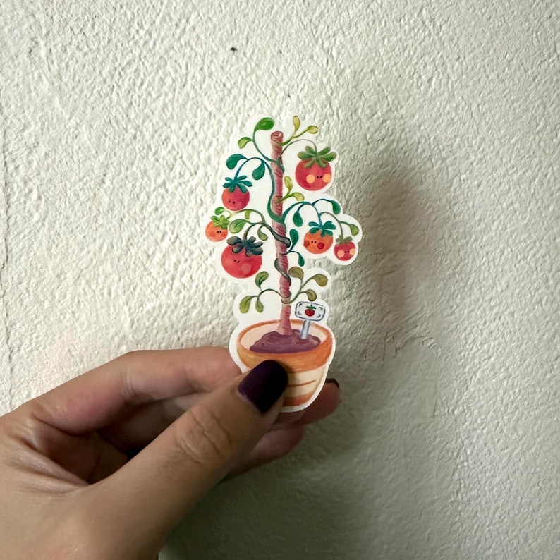 May include: A sticker featuring a cartoon tomato plant in a pot. The plant has red tomatoes with green leaves and a brown stem. The pot is orange and brown. A small sign is at the base of the plant.