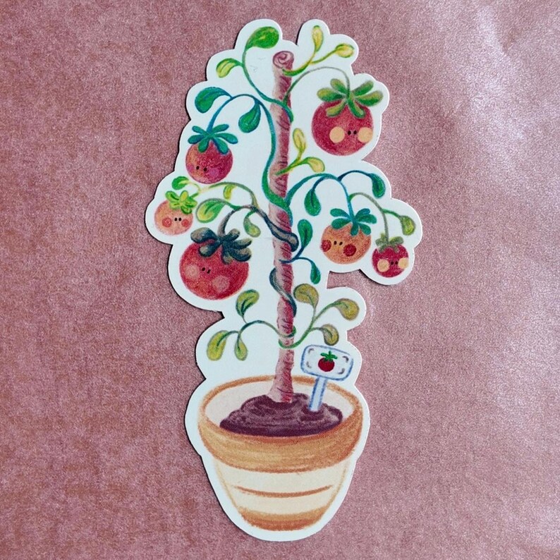 May include: A whimsical sticker featuring a cartoon tomato tree in a pot. The tree has red tomatoes with smiling faces, green leaves, and a sign with a tomato illustration. The pot is beige with brown soil.