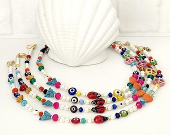May include: Five colourful beaded necklaces with white pearls, evil eye charms, ladybugs, and other decorative beads.