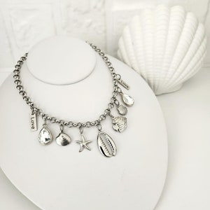 May include: A silver chain necklace with multiple charms, including seashells, a starfish, and two tags that say "Love".