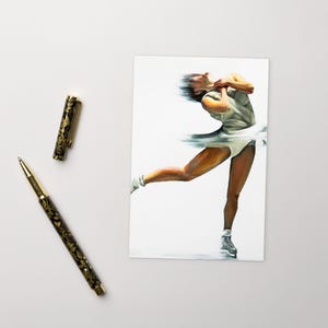 Op de afbeelding: Een artistieke print van een kunstschaatser in beweging, gekleed in een witte turnpakje en rok, met een vervaagd effect dat snelheid suggereert. Een gouden en zwarte pen met bloemendetails ligt naast de print.