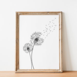 May include: A framed black and white print of two dandelion flowers with seeds blowing in the wind. The print is in a light wood frame.