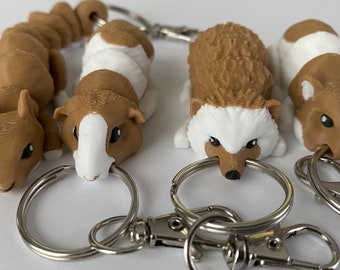 May include: A collection of animal-themed keychains. The keychains feature detailed 3D-printed designs of a squirrel, guinea pig, hedgehog, and hamster. Each keychain has a silver-colored metal ring and clasp for attaching to keys or bags.