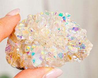 May include: A cluster of iridescent white quartz crystals with a rainbow sheen. The crystals are clustered together in a natural formation, creating a unique and beautiful piece.