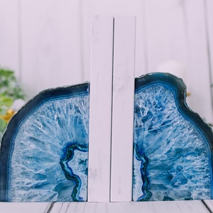 May include: A pair of blue agate bookends with white backing. The agate is a natural stone with a unique pattern of blue and white.