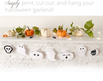 Op de afbeelding: Een witte bakstenen schouwmantel versierd met een krans van witte pompoenen en groene bladeren. Een Halloween-banner hangt onder de schouwmantel met uitsparingen van geesten, pompoenen, een schedel en een mummie.