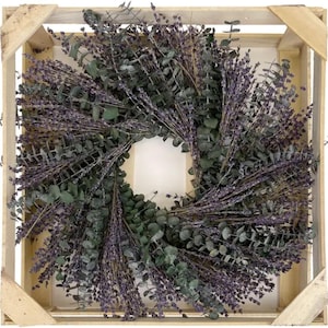 May include: A wreath made of dried lavender and eucalyptus branches. The wreath is in a wooden crate.