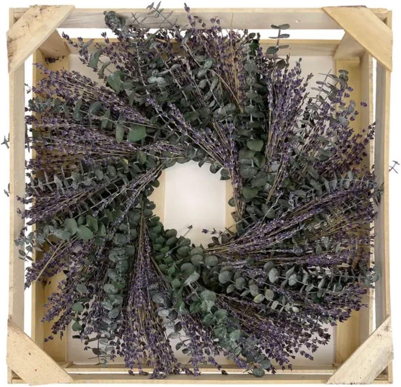May include: A wreath made of dried lavender and eucalyptus branches. The wreath is in a wooden crate.