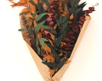 May include: A bouquet of dried eucalyptus leaves in shades of green, orange, and burgundy, wrapped in brown paper. The leaves have various shapes and textures, creating a natural and rustic aesthetic. The bouquet is tied with twine.