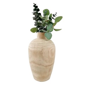 May include: A light brown wooden vase with a smooth, rounded shape. The vase is empty and has a natural wood grain pattern.