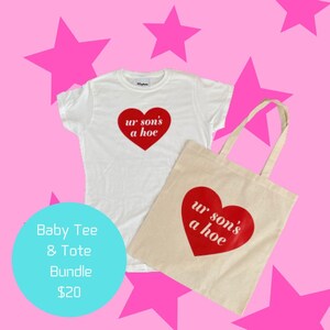 Puede incluir: Una camiseta blanca para bebé y una bolsa de lona natural, ambas con un corazón rojo con el texto "ur son's a hoe" en blanco. Los artículos se muestran sobre un fondo rosa con estrellas rosas.