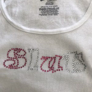 May include: White tank top with the word "BRIDES" spelled out in rhinestones. The "B" and "S" are pink, the "R" and "I" are silver, and the "D" and "E" are pink.