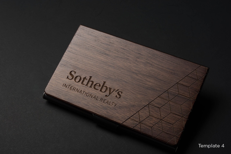 May include: A dark brown wooden business card holder with a geometric pattern and the text "Sotheby's International Realty" engraved on the front.