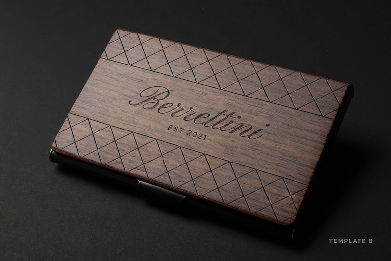 May include: A wooden business card holder with a diamond pattern and the text "Berrettini EST 2021" engraved on the front.