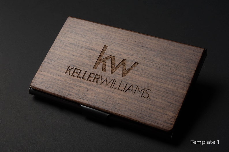 May include: A wooden business card holder with a black metal edge. The holder is engraved with the Keller Williams logo and the text "Keller Williams".