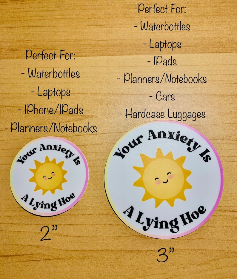 May include: Two round stickers with the text "Your Anxiety Is A Lying Hoe" and a smiling sun graphic. One sticker is 2 inches, the other is 3 inches. The stickers are white with a pink and yellow gradient border.