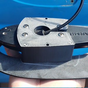 May include: A black Garmin fish finder transducer mounted on a gray plastic bracket. The bracket has several screw holes and is designed to be attached to a boat or kayak.