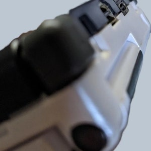 May include: Close-up of a white and black handheld device with a black rubberized grip and a USB-C port on the side.