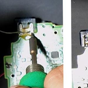 May include: Close-up of a circuit board with a soldering iron in use. The board is green with various components and a small connector. A thin wire is being soldered to the connector. The image shows the process of electronics repair or modification.