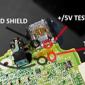 May include: Close-up of a circuit board with various components and text labels. Key labels include "-/GND SHIELD", "+/5V TESTPOINT", "TP119 -/GND", and "TP118 +/5V". Red circles highlight specific points on the board.