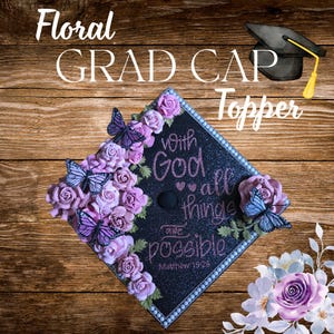 Op de afbeelding: Een bloemen afstudeerhoed topper met de tekst "Floral GRAD CAP Topper". De zwarte dop is versierd met roze rozen, paarse vlinders en de zin "With God all things are possible" in roze glitter.