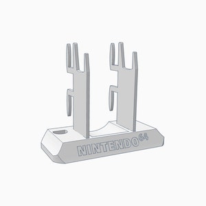 Puede incluir: Un soporte de plástico gris para cartuchos de juegos de Nintendo 64. El soporte tiene dos ranuras verticales para sujetar los cartuchos y una base con el texto "NINTENDO 64" impreso en él.