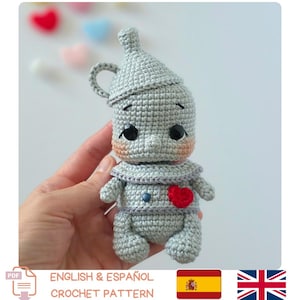 Peut inclure: Une poupée crochetée grise en forme de personnage en fer-blanc avec un chapeau en entonnoir, une petite anse sur le côté de la tête, des yeux noirs, des joues roses et un cœur rouge cousu sur la poitrine. Texture en fil gris métallique.