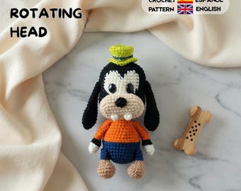 Könnte beinhalten: Eine Häkelpuppe eines schwarz-weißen Hundes mit lindgrünem Hut, orangefarbenem Oberteil und blauer Hose, zwei weißen Zähnen und schwarzen Augen. Text 360 ROTATING HEAD, CROCHET PATTERN, ESPAÑOL, ENGLISH. Ein knochenförmiges Holzobjekt liegt daneben.