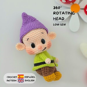 May include: A crocheted gnome doll featuring a purple pointed hat, a light green tunic with a black belt, and brown trousers with yellow shoes. The doll has large black eyes and pink cheeks. Text reads 360 ROTATING HEAD LOW-SEW CROCHET PATTERN ESPAÑOL ENGLISH.
