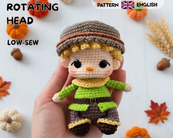 Könnte beinhalten: Eine kleine gehäkelte Puppe mit braunem Hut, gelben Haaren und einem grünen Hemd mit braunem Gürtel. Die Puppe hat große schwarze Augen und eine kleine orangefarbene Nase. Der Text lautet 360 ROTATING HEAD, LOW-SEW, CROCHET PATTERN, ESPAÑOL, ENGLISH.
